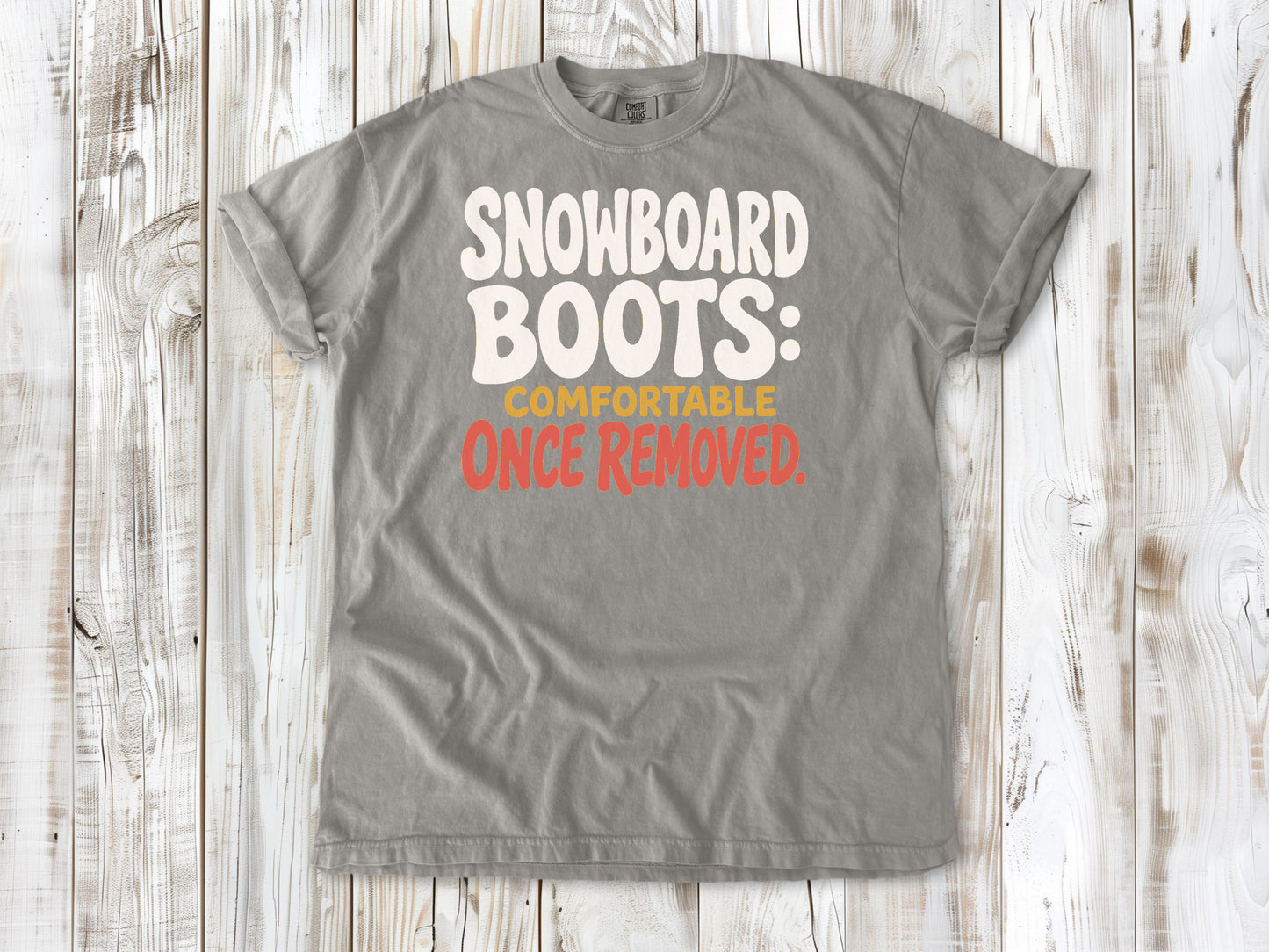 Khaki garment-dyed tee with Snowboard Boots Comfortable Once Removed graphic.