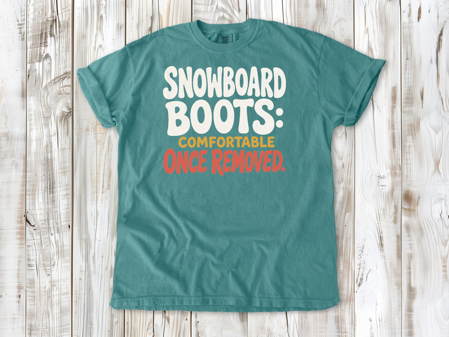 Mustard garment-dyed tee with Snowboard Boots Comfortable Once Removed graphic.