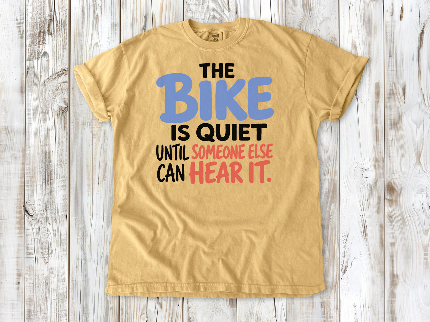 Burnt Orange garment-dyed tee with The Bike Is Quiet Until Someone Else Can Hear It cycling graphic.