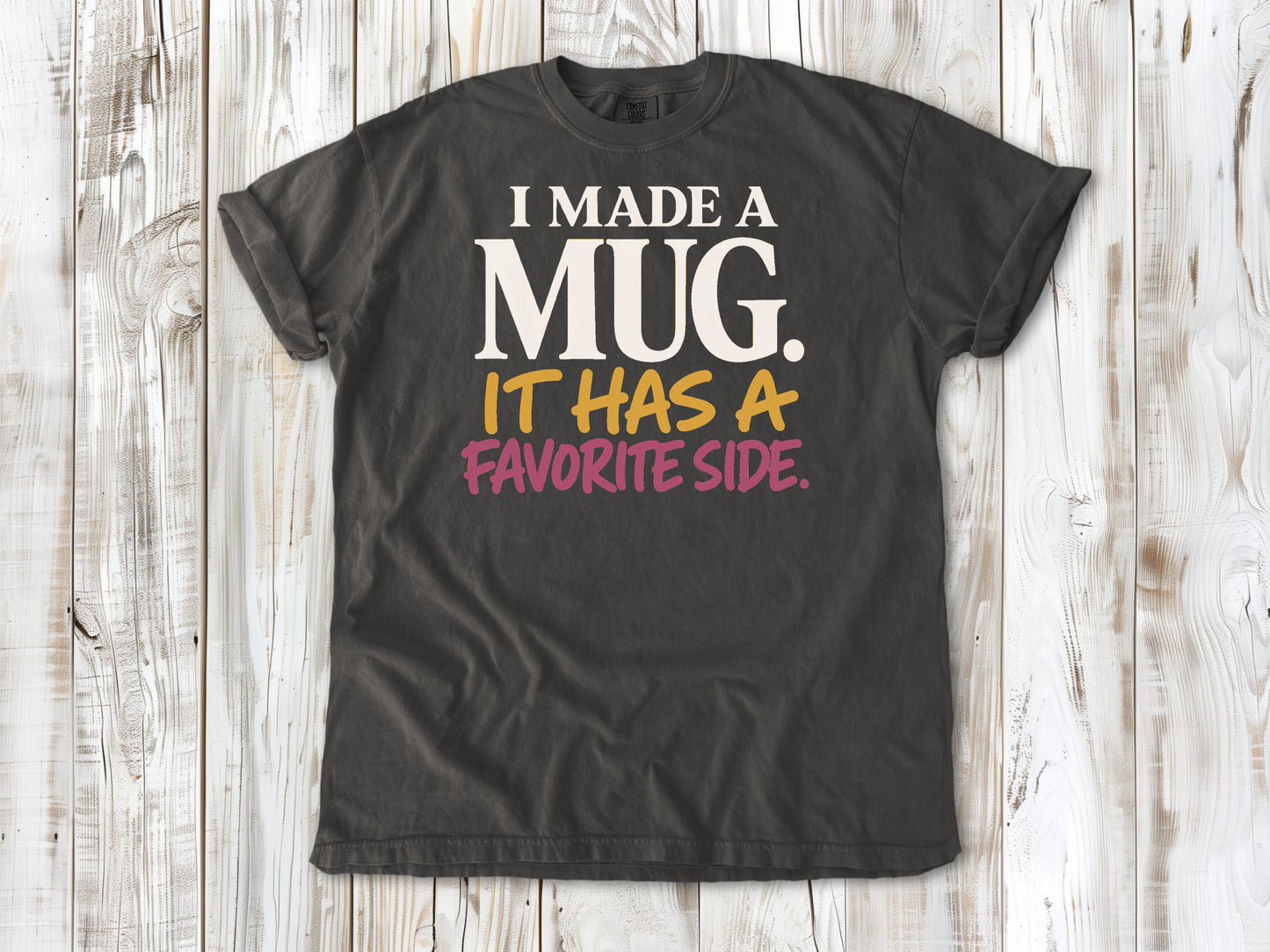Ivory garment-dyed tee with I Made a Mug It Has a Favorite Side pottery graphic.