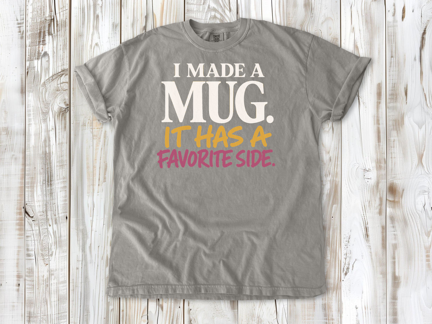 Khaki garment-dyed tee with I Made a Mug It Has a Favorite Side pottery graphic.