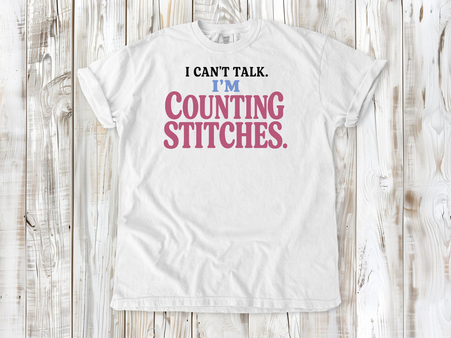 White garment-dyed tee with I Can't Talk I'm Counting Stitches knitting and crochet graphic.