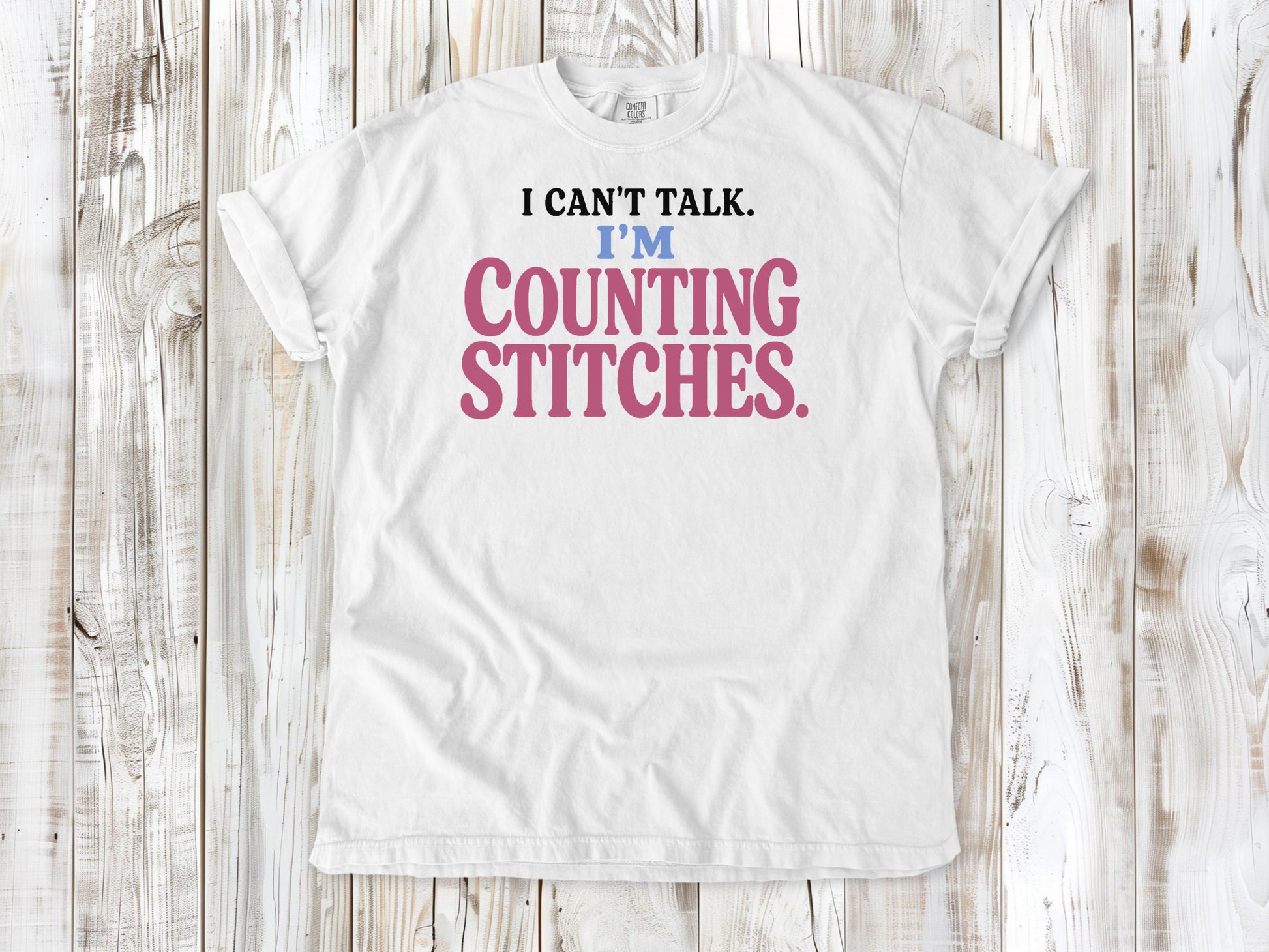 White garment-dyed tee with I Can't Talk I'm Counting Stitches knitting and crochet graphic.