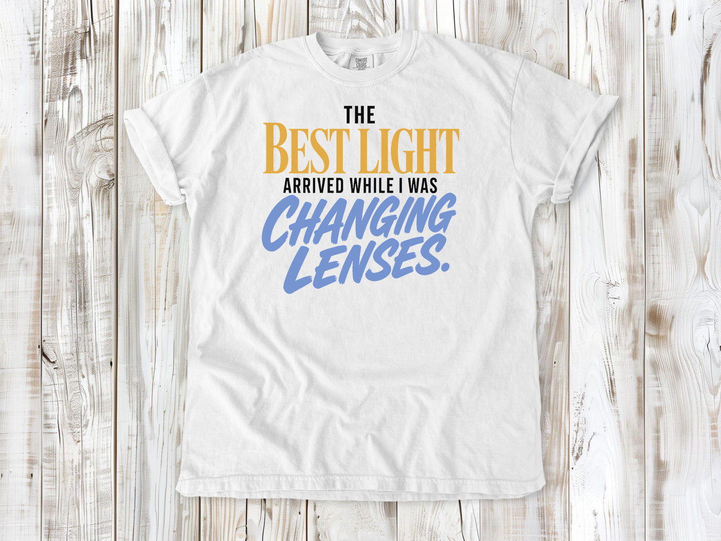 White garment-dyed tee with The Best Light Arrived While I Was Changing Lenses photography graphic.