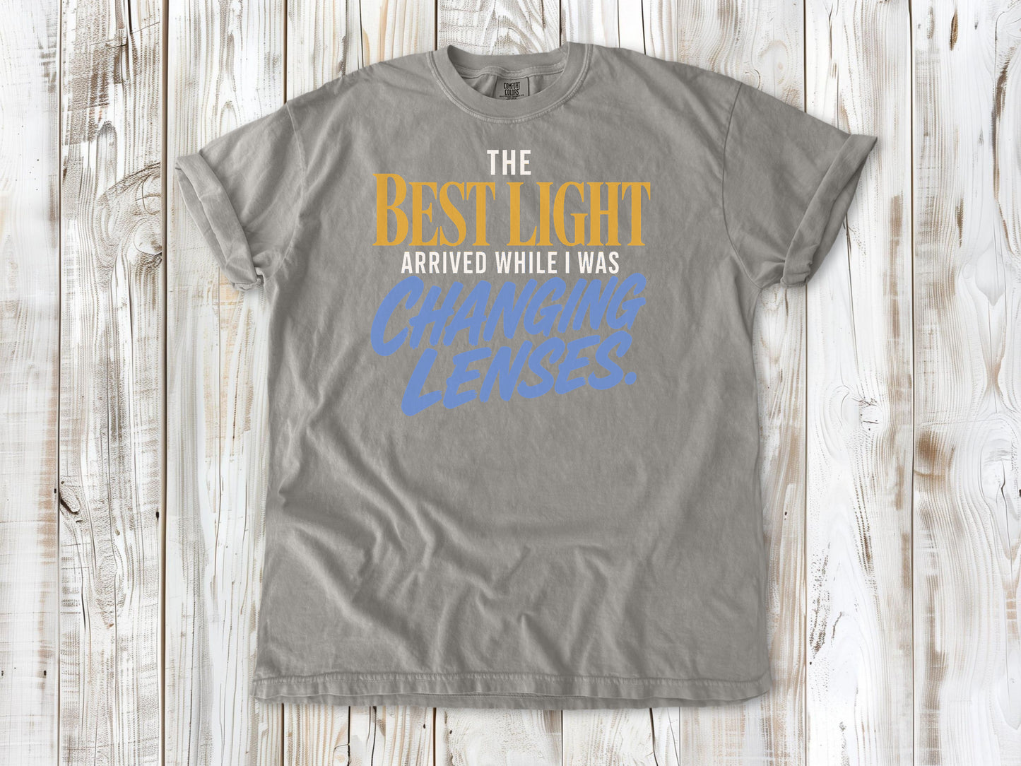 Khaki garment-dyed tee with The Best Light Arrived While I Was Changing Lenses photography graphic.