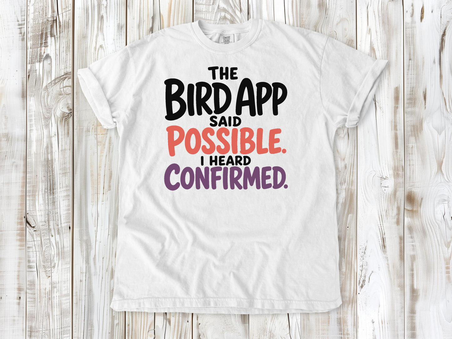 White garment-dyed tee with The Bird App Said Possible I Heard Confirmed birding graphic.
