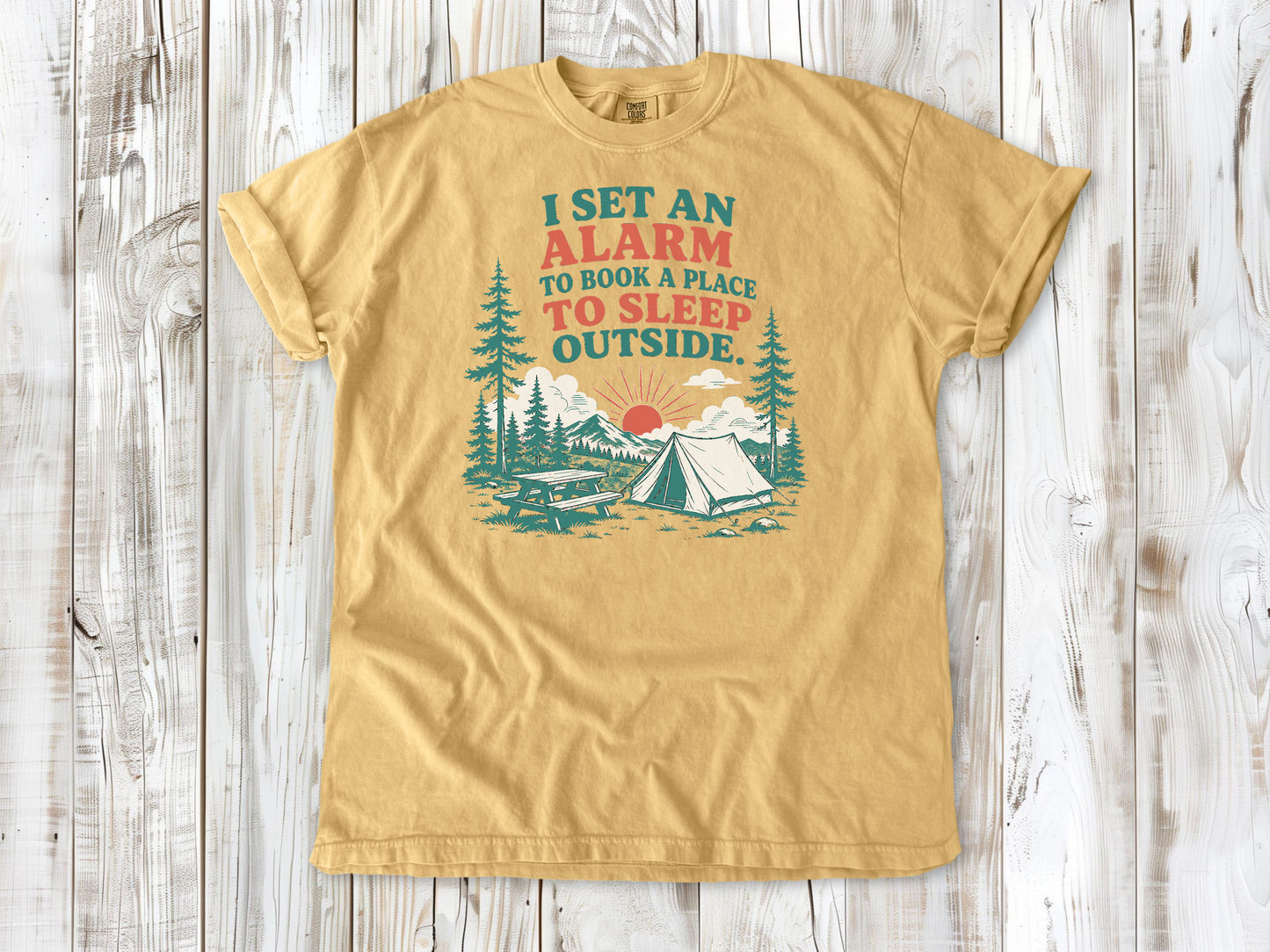Mustard garment-dyed tee with I Set an Alarm to Book a Place to Sleep Outside camping graphic.