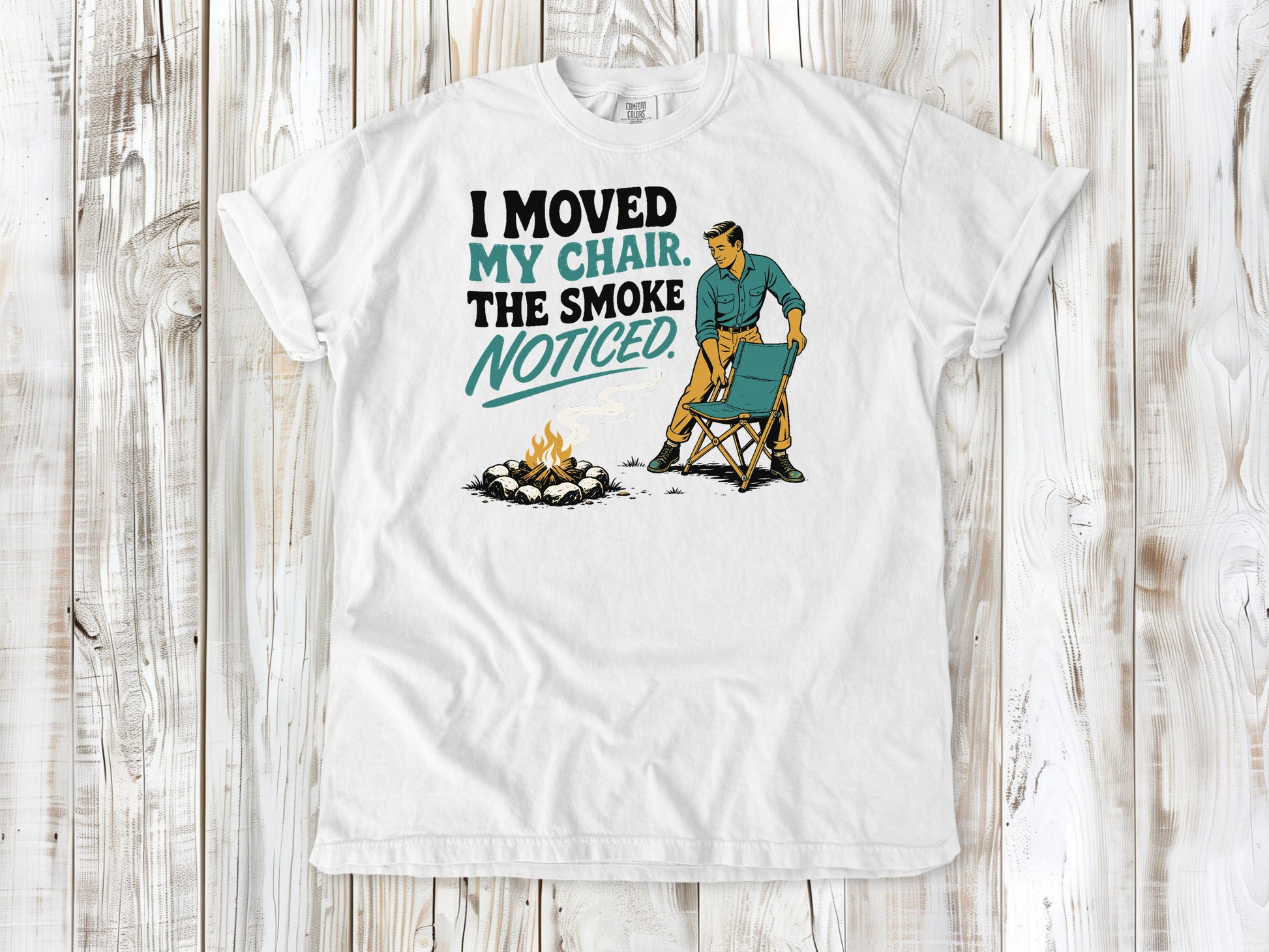 White garment-dyed tee with I Moved My Chair The Smoke Noticed campfire graphic.