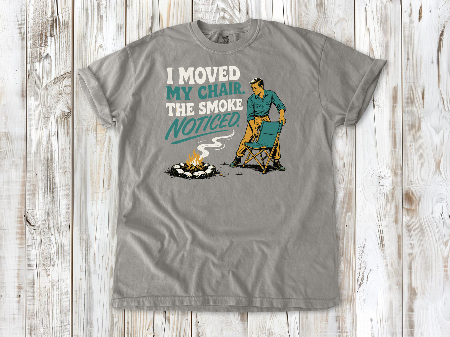 Khaki garment-dyed tee with I Moved My Chair The Smoke Noticed campfire graphic.