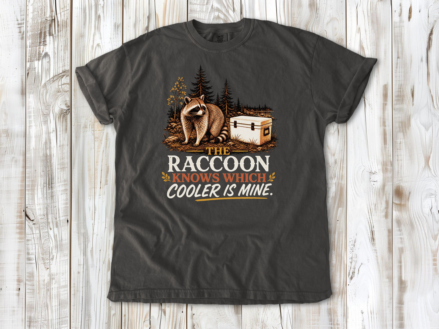 Ivory garment-dyed tee with The Raccoon Knows Which Cooler Is Mine camping graphic.