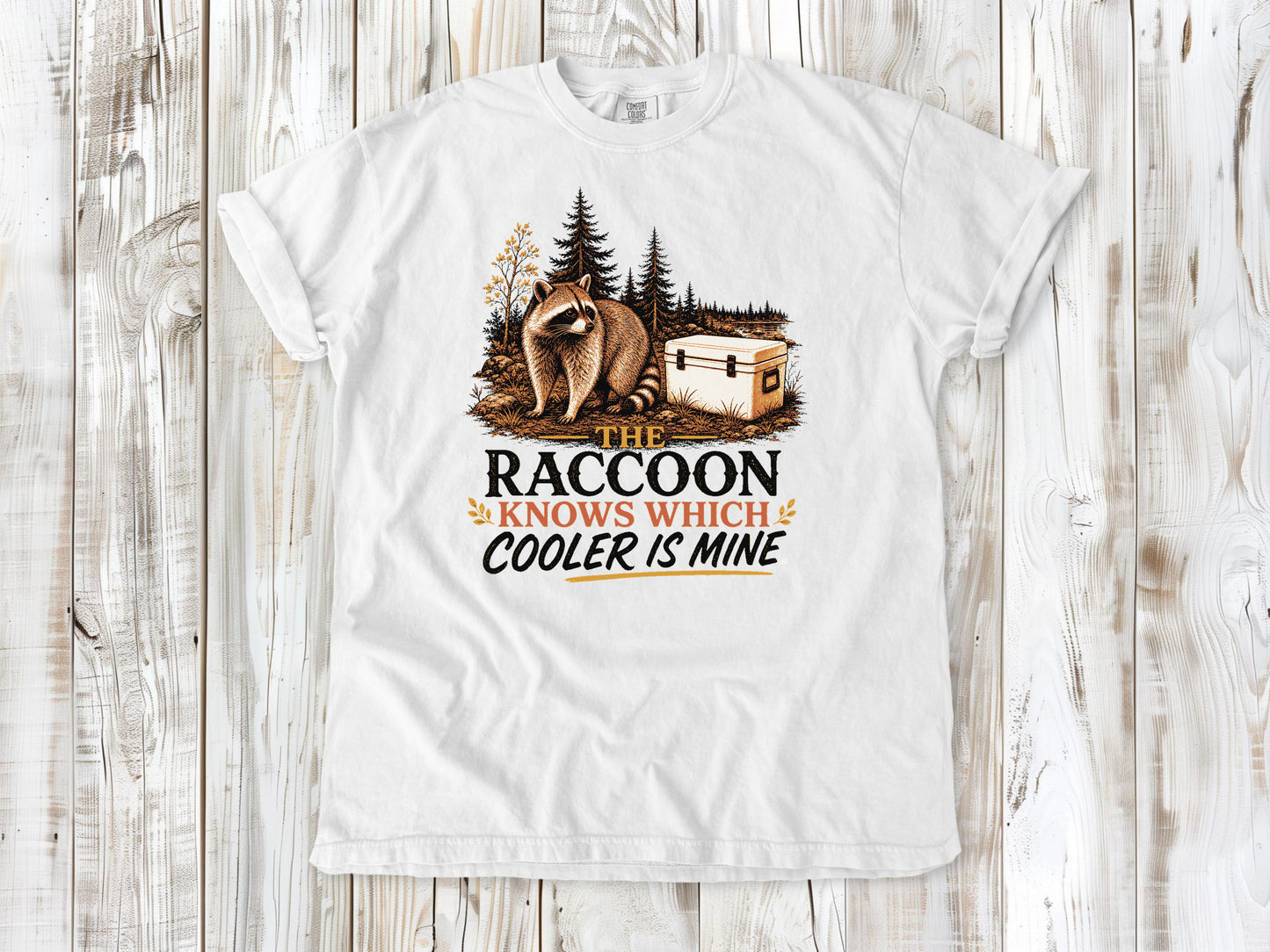 White garment-dyed tee with The Raccoon Knows Which Cooler Is Mine camping graphic.