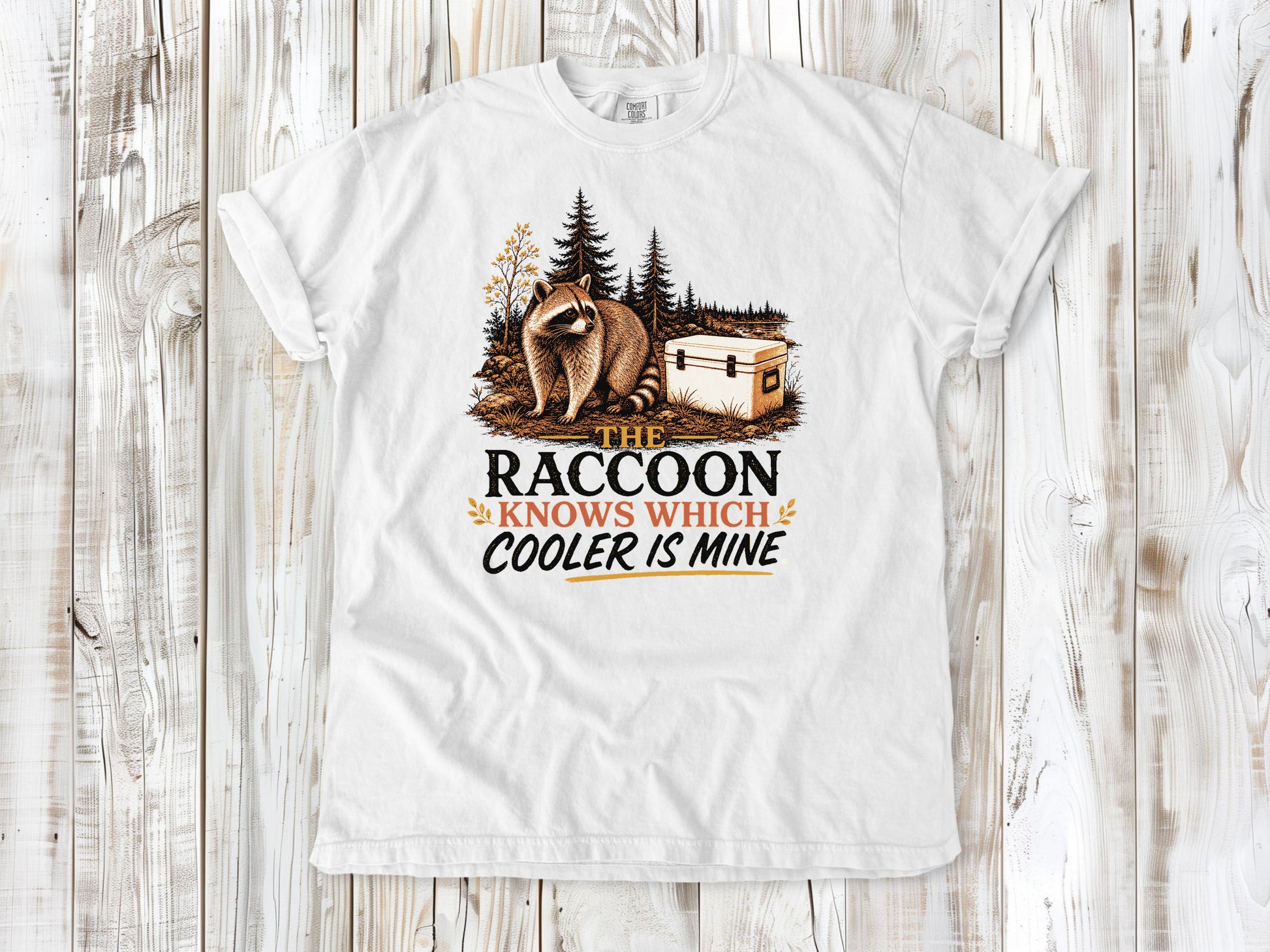 White garment-dyed tee with The Raccoon Knows Which Cooler Is Mine camping graphic.