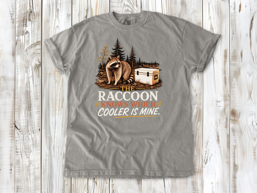 Khaki garment-dyed tee with The Raccoon Knows Which Cooler Is Mine camping graphic.