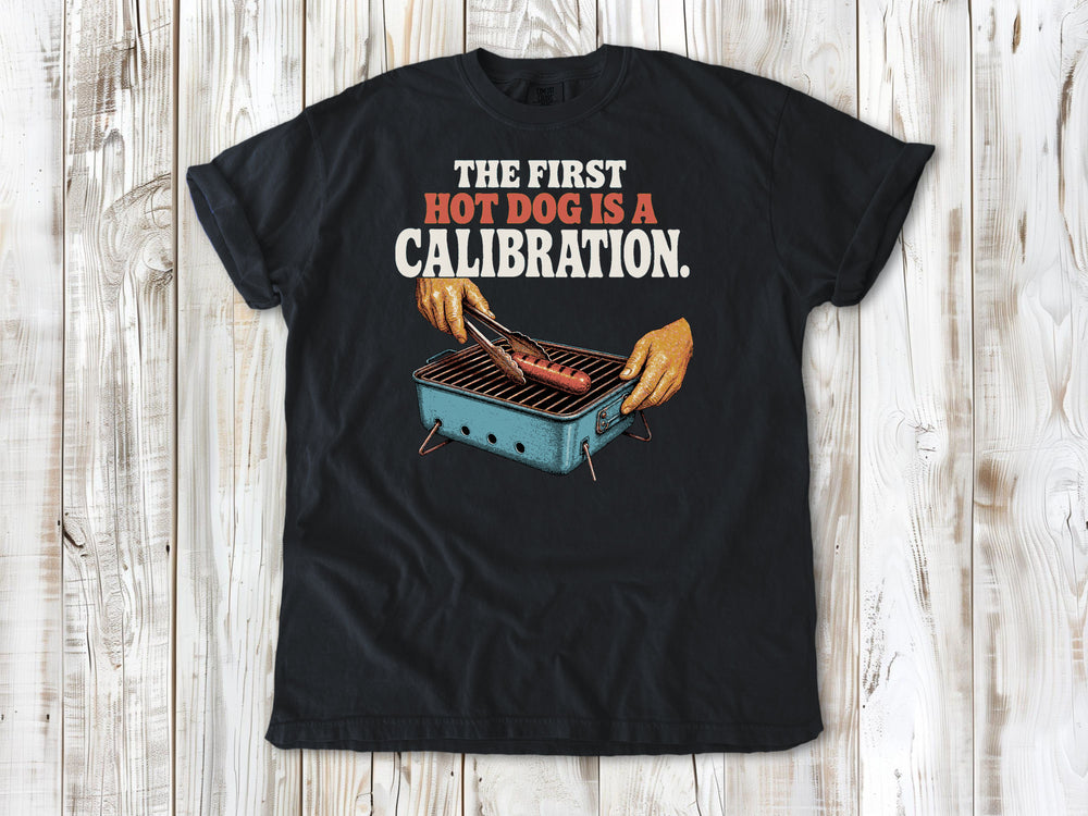 Washed Denim garment-dyed tee with The First Hot Dog Is a Calibration beach grilling graphic.