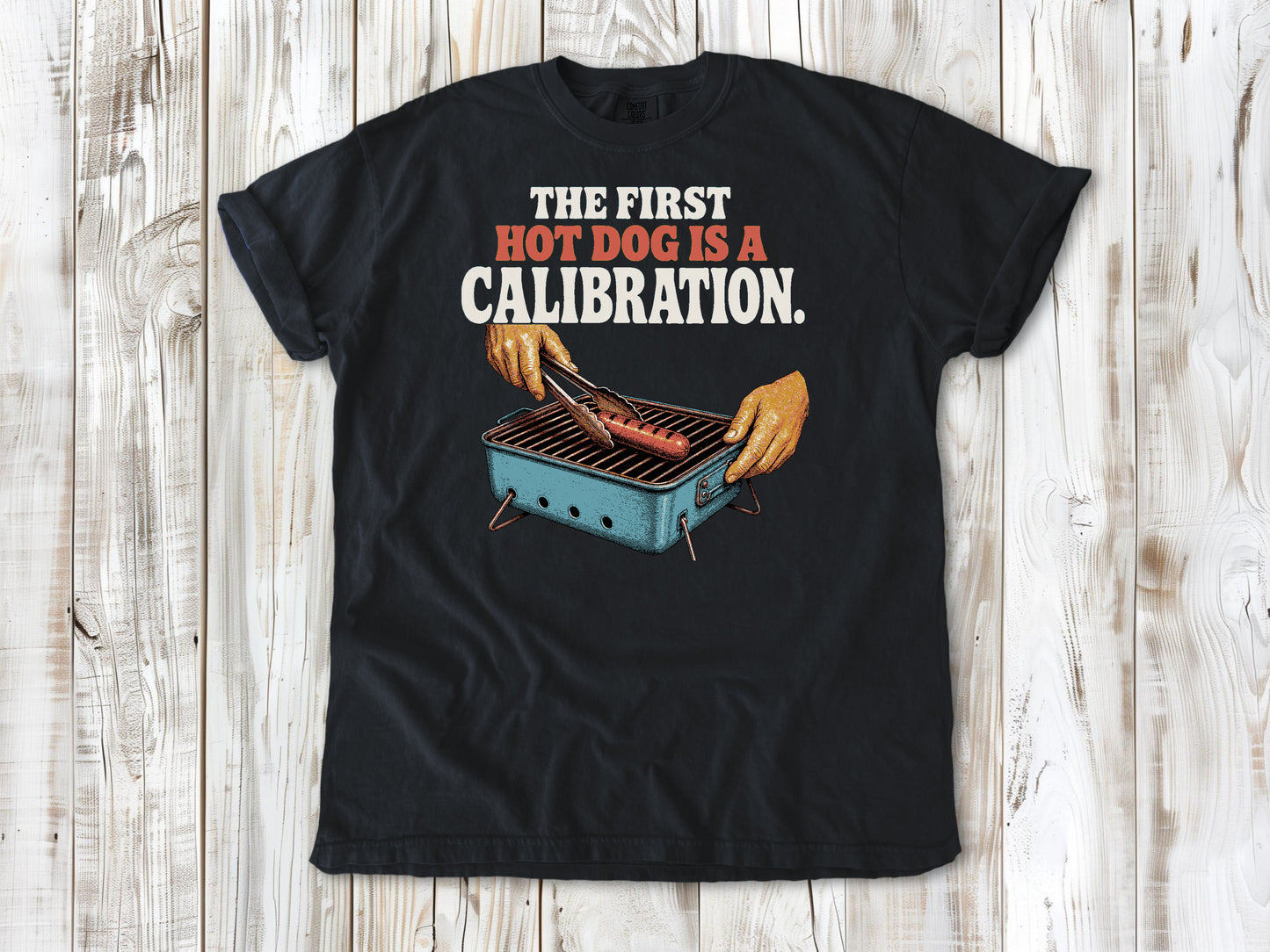 Washed Denim garment-dyed tee with The First Hot Dog Is a Calibration beach grilling graphic.