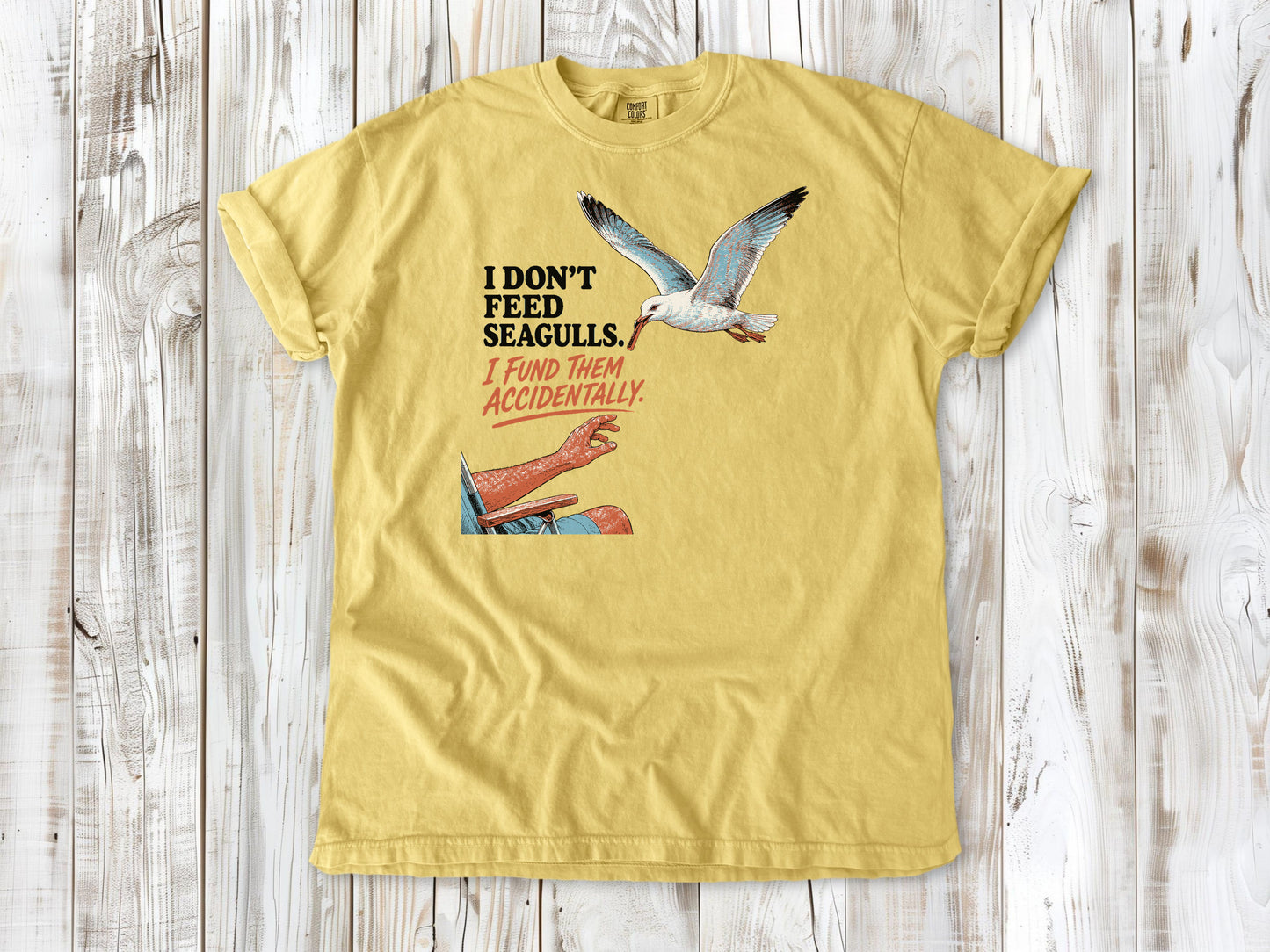 Grey garment-dyed tee with I Don't Feed Seagulls I Fund Them Accidentally beach graphic.