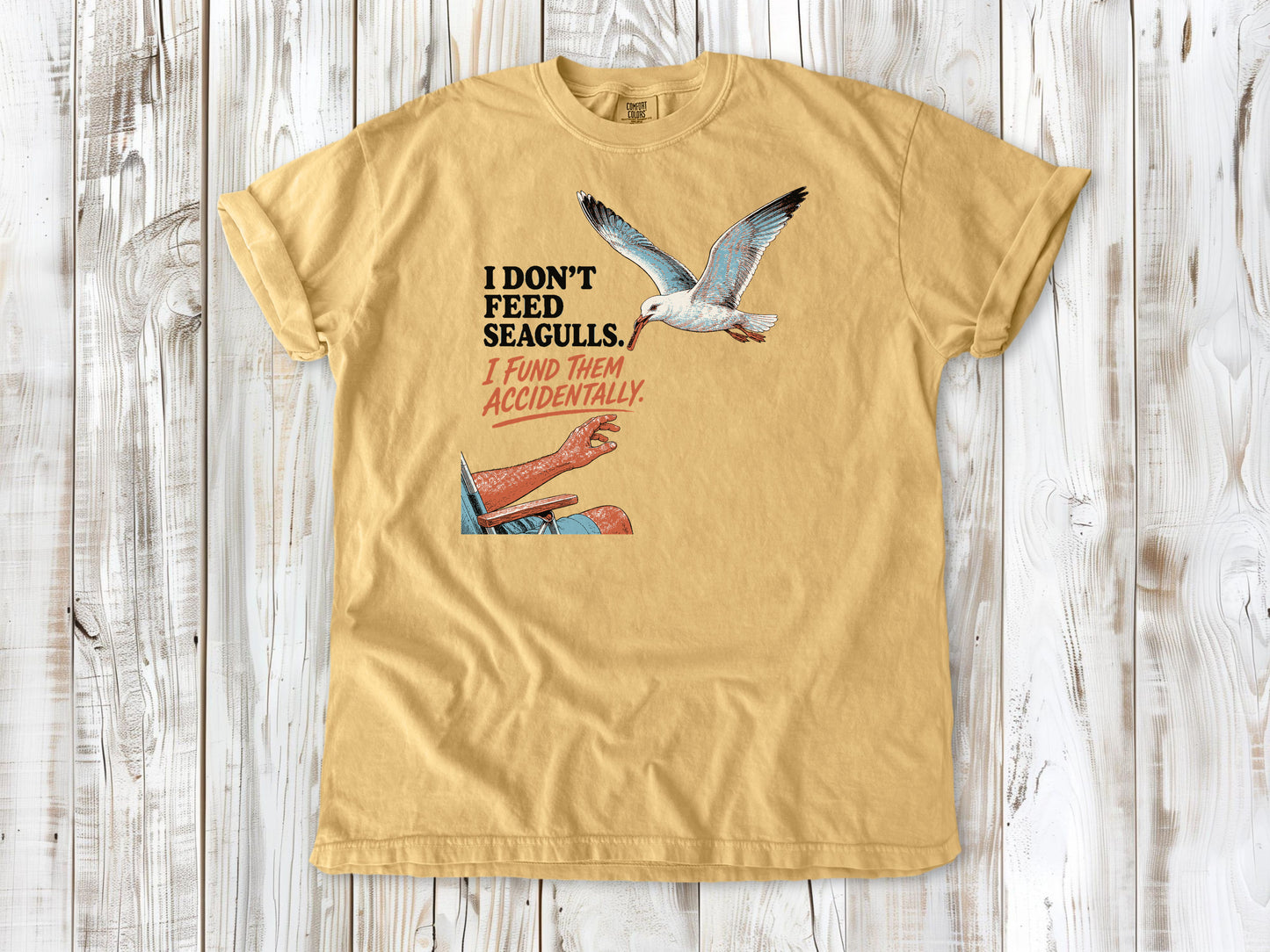 Burnt Orange garment-dyed tee with I Don't Feed Seagulls I Fund Them Accidentally beach graphic.