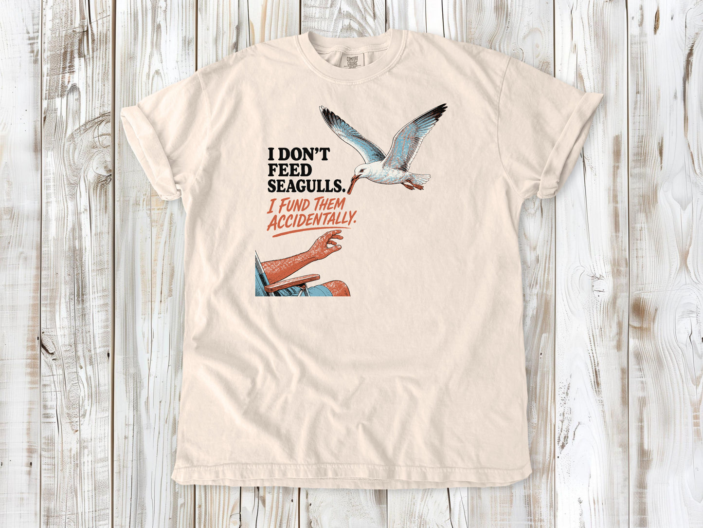 Butter garment-dyed tee with I Don't Feed Seagulls I Fund Them Accidentally beach graphic.