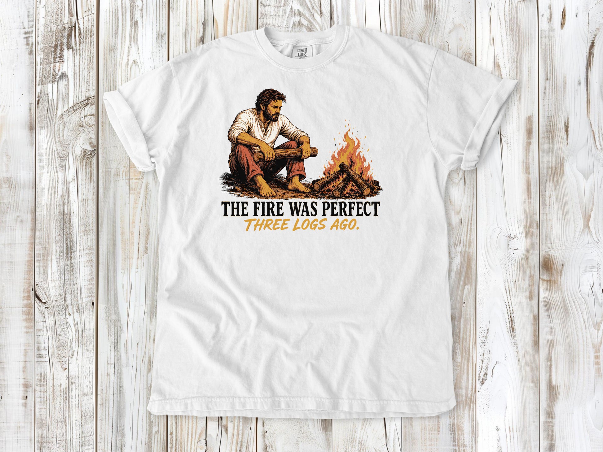 White garment-dyed tee with The Fire Was Perfect Three Logs Ago beach bonfire graphic.