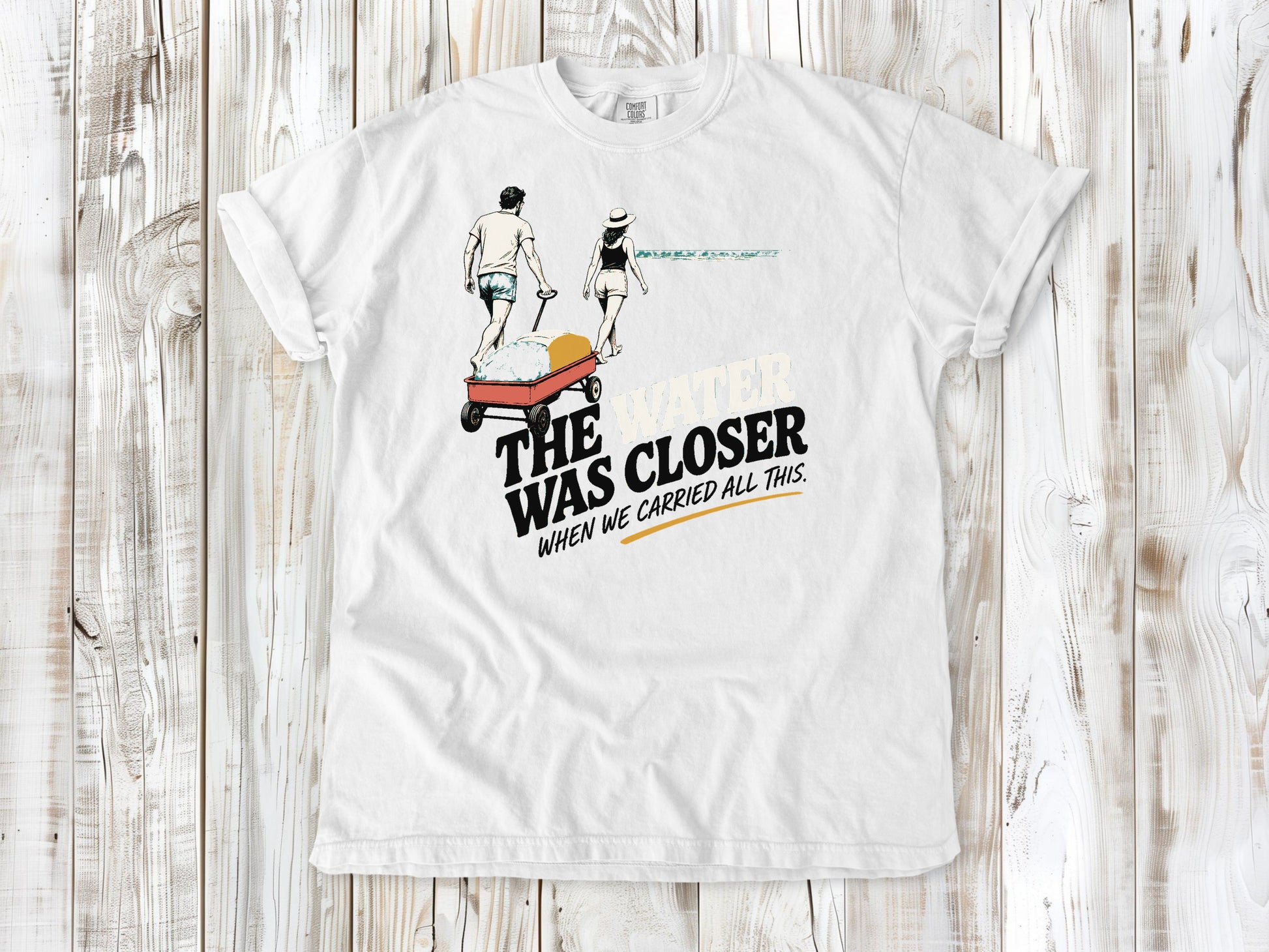 White garment-dyed tee with The Water Was Closer When We Carried All This beach graphic.