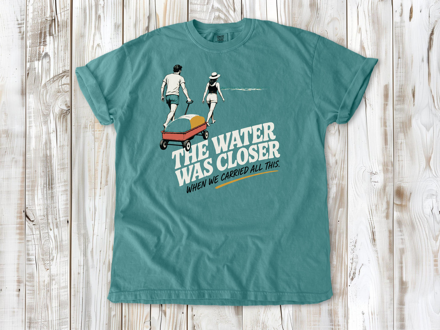 Mustard garment-dyed tee with The Water Was Closer When We Carried All This beach graphic.