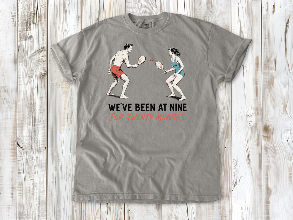 Khaki garment-dyed tee with We've Been at Nine for Twenty Minutes beach paddleball graphic.