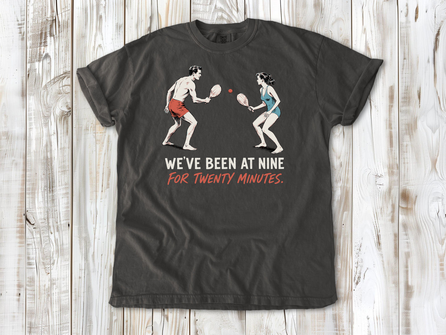 Ivory garment-dyed tee with We've Been at Nine for Twenty Minutes beach paddleball graphic.