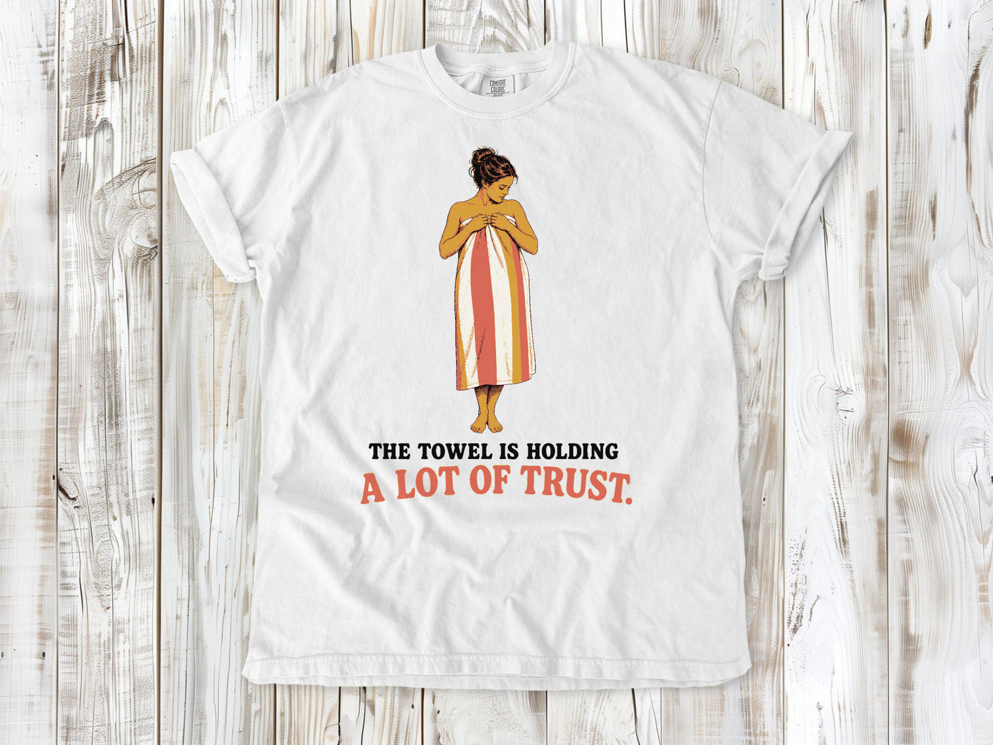White garment-dyed tee with The Towel Is Holding a Lot of Trust beach graphic.