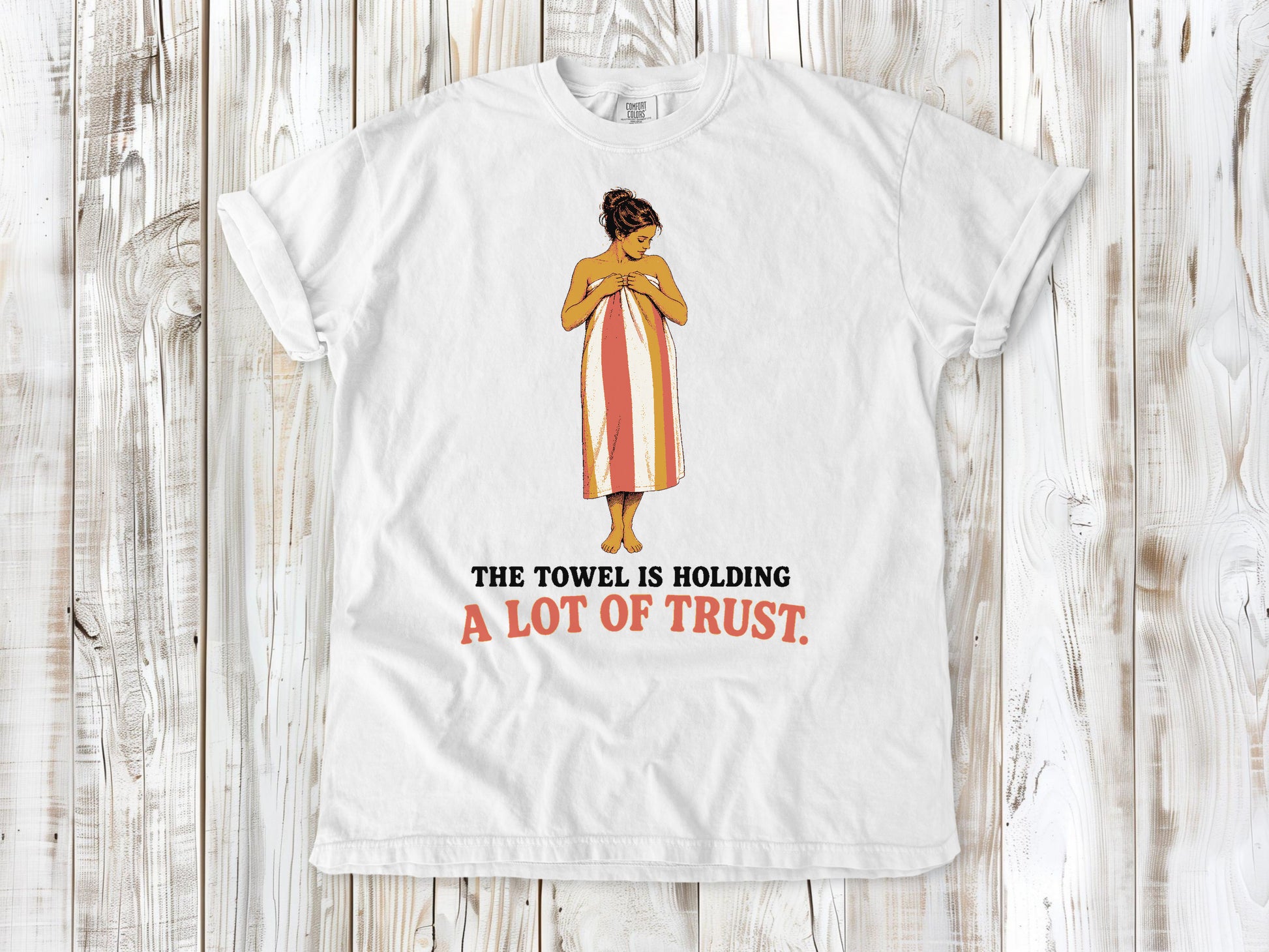 White garment-dyed tee with The Towel Is Holding a Lot of Trust beach graphic.