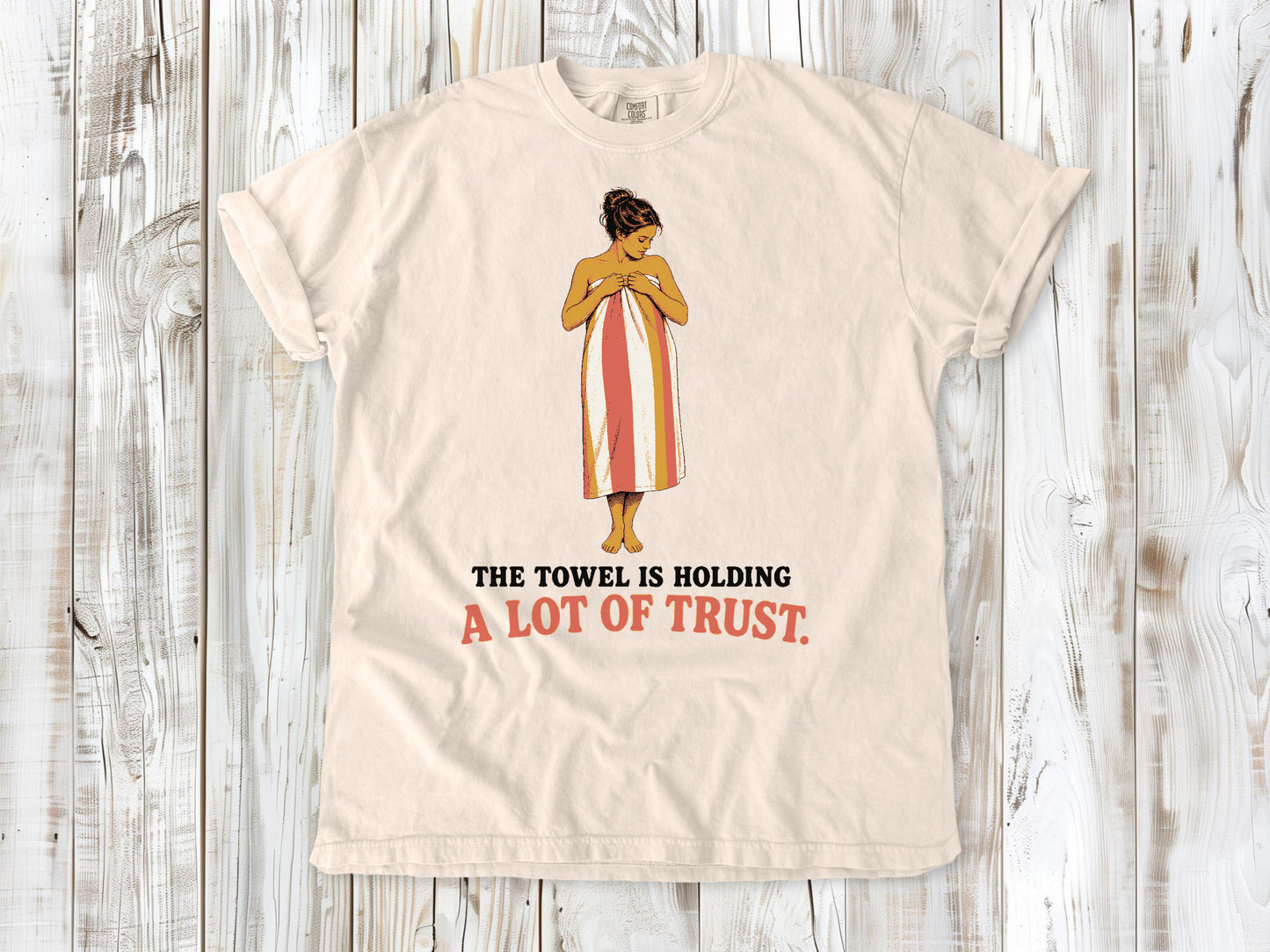 Butter garment-dyed tee with The Towel Is Holding a Lot of Trust beach graphic.