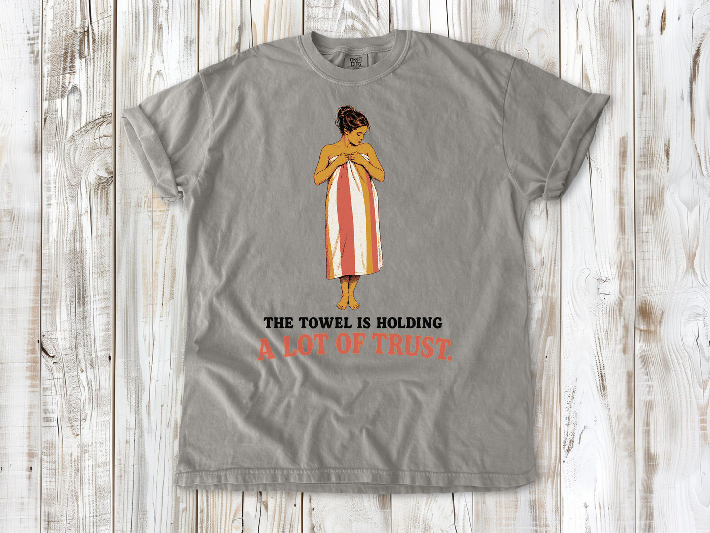 Khaki garment-dyed tee with The Towel Is Holding a Lot of Trust beach graphic.