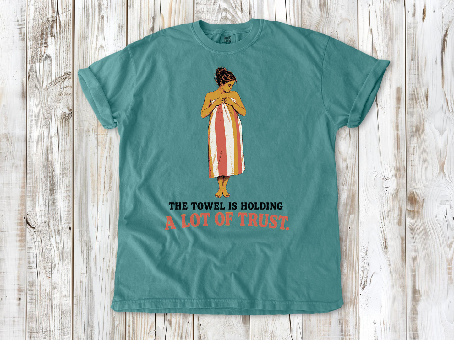Mustard garment-dyed tee with The Towel Is Holding a Lot of Trust beach graphic.