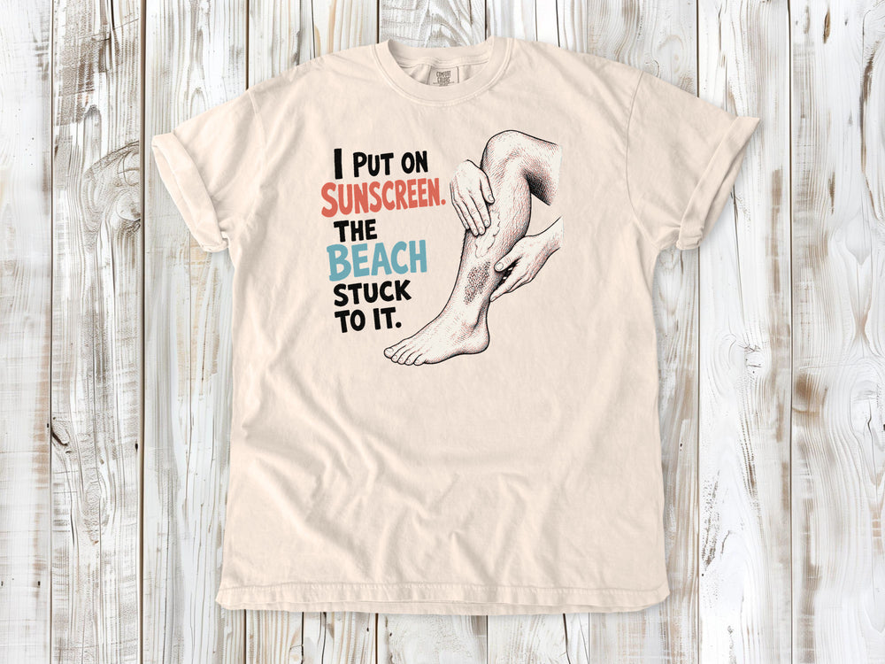 Butter garment-dyed tee with I Put on Sunscreen The Beach Stuck to It graphic.