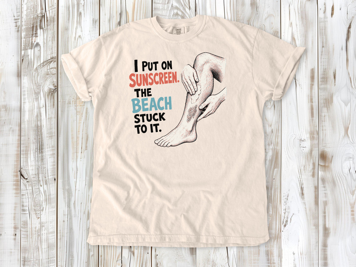 Butter garment-dyed tee with I Put on Sunscreen The Beach Stuck to It graphic.