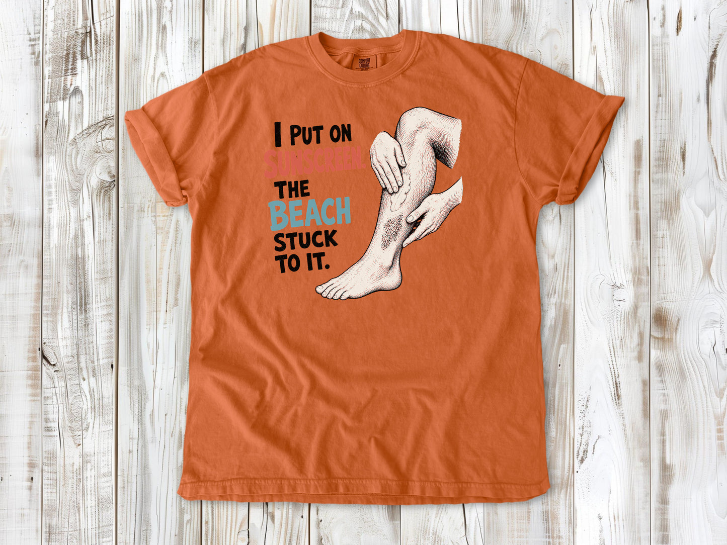 Seafoam garment-dyed tee with I Put on Sunscreen The Beach Stuck to It graphic.