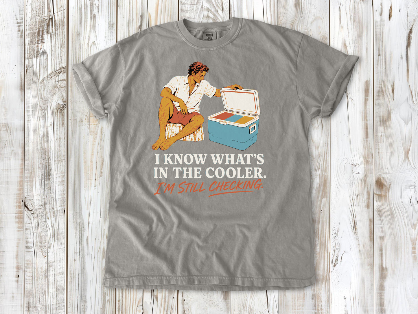 Khaki garment-dyed tee with I Know What's in the Cooler I'm Still Checking beach graphic.