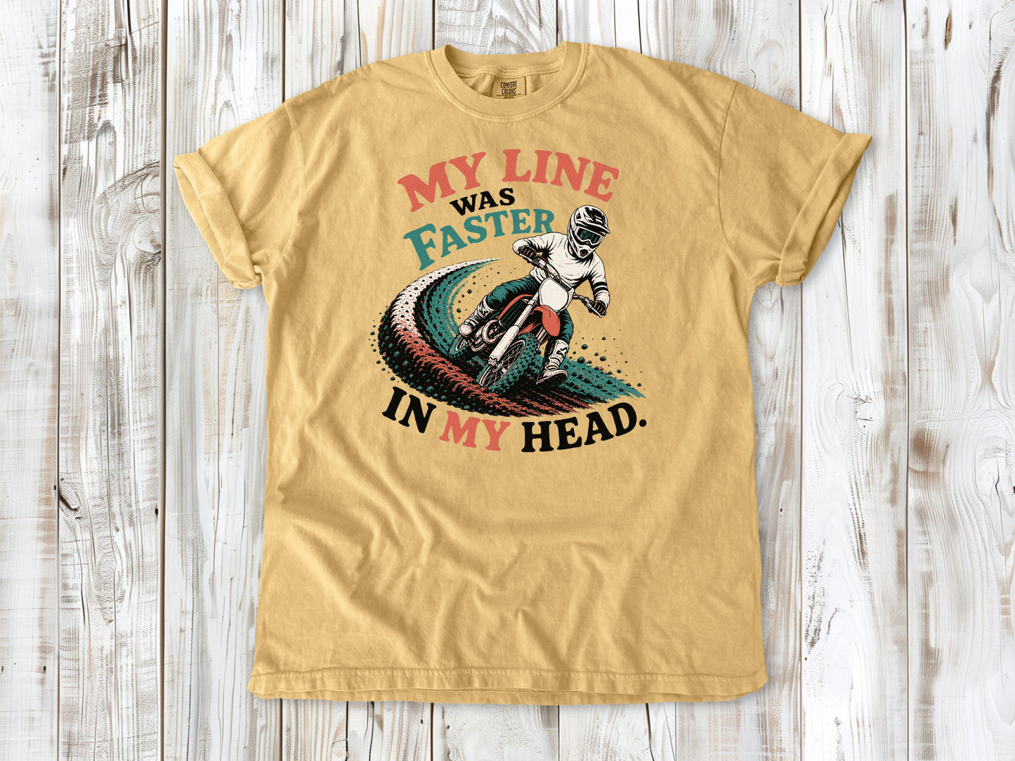 Mustard garment-dyed tee with My Line Was Faster in My Head motocross rider graphic.