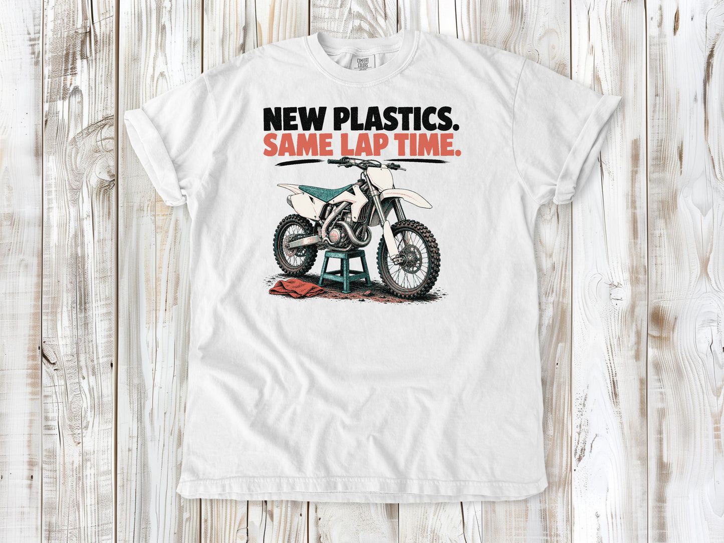 White garment-dyed tee with New Plastics Same Lap Time dirt bike graphic.