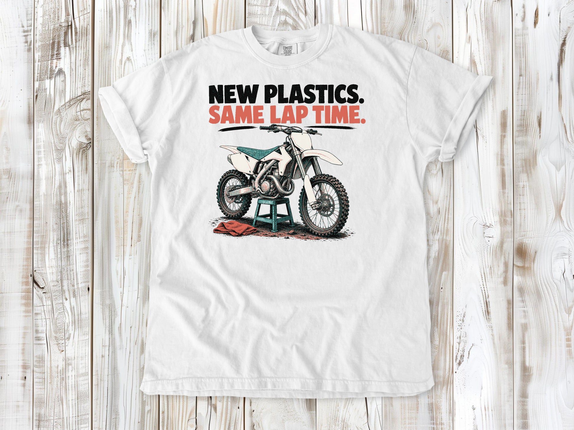 White garment-dyed tee with New Plastics Same Lap Time dirt bike graphic.