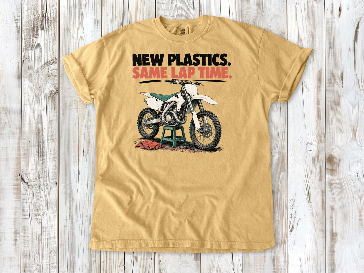 Mustard garment-dyed tee with New Plastics Same Lap Time dirt bike graphic.