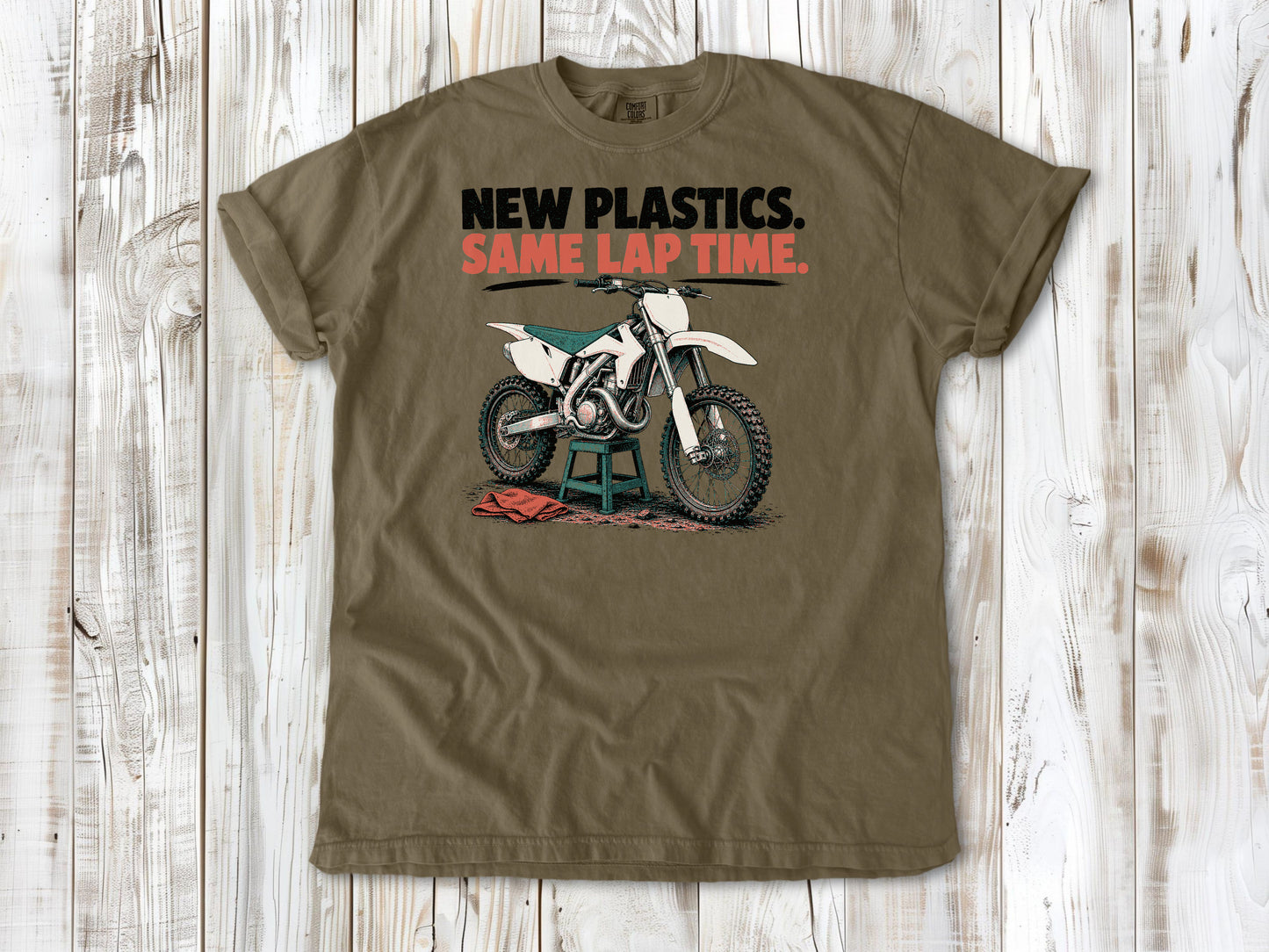 Khaki garment-dyed tee with New Plastics Same Lap Time dirt bike graphic.