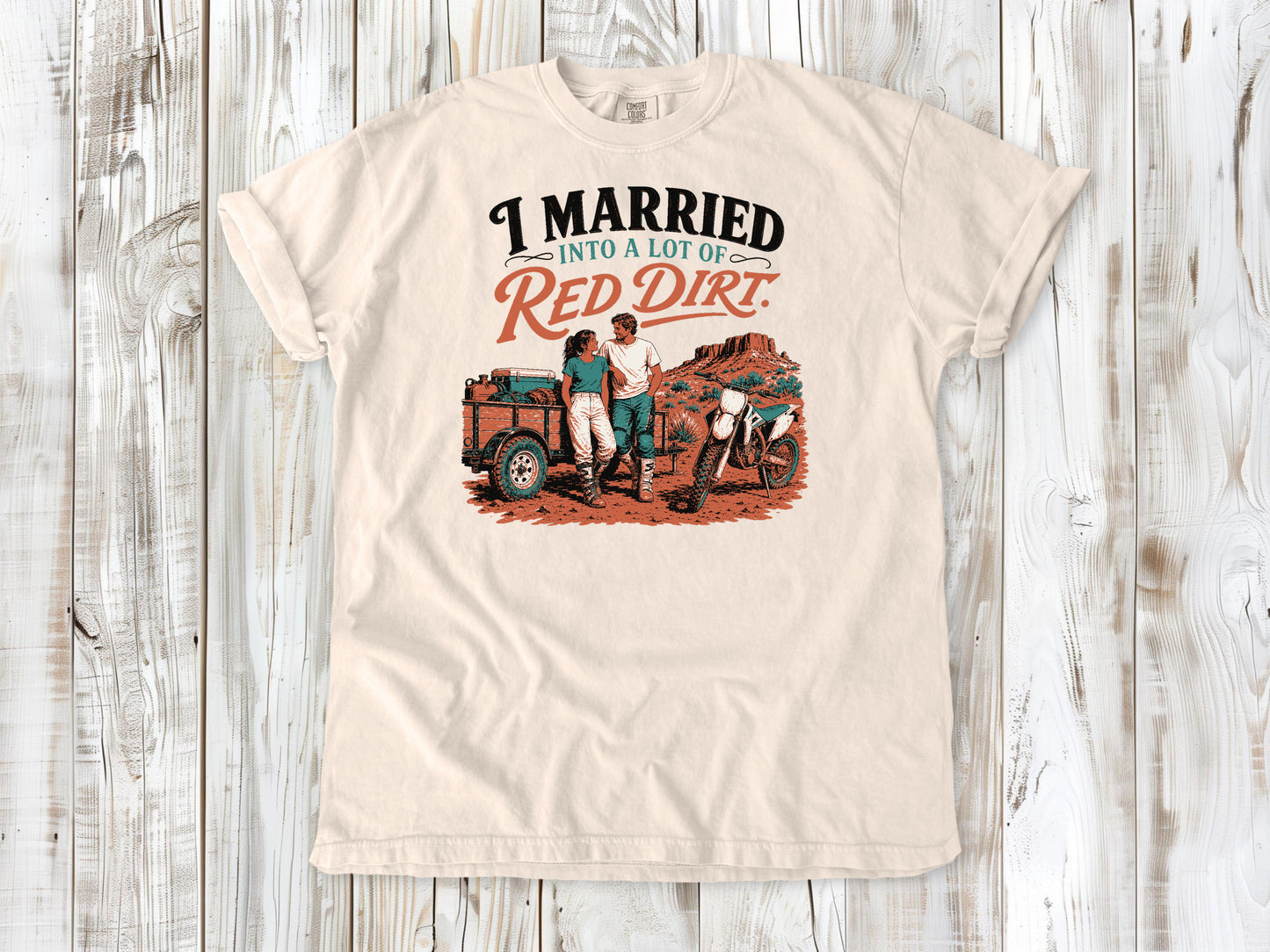 Ivory garment-dyed tee with I Married Into a Lot of Red Dirt motocross couple graphic.