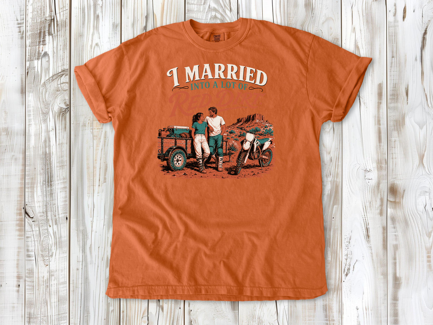 Burnt Orange garment-dyed tee with I Married Into a Lot of Red Dirt motocross couple graphic.