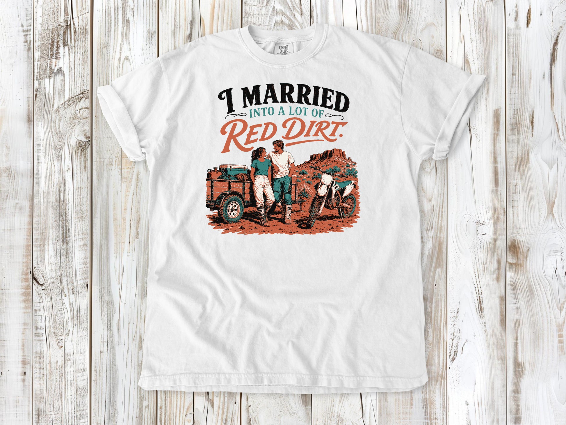White garment-dyed tee with I Married Into a Lot of Red Dirt motocross couple graphic.
