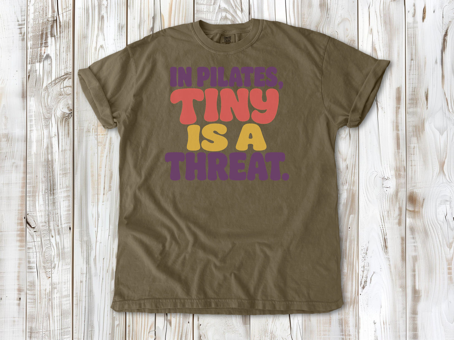 Khaki garment-dyed tee with In Pilates Tiny Is a Threat studio humor graphic.