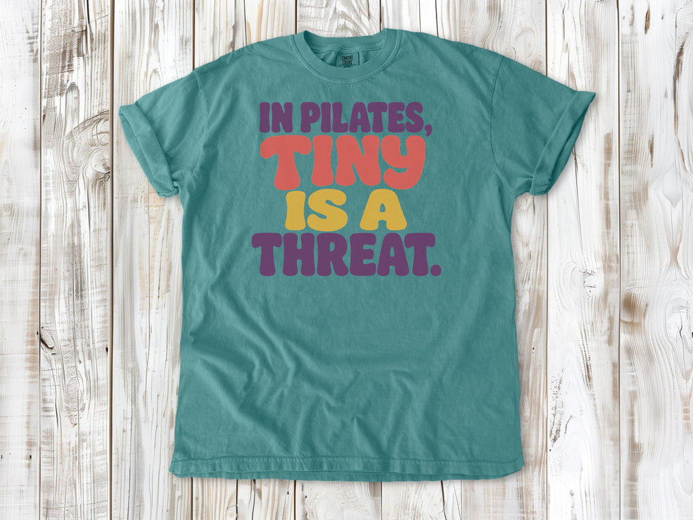 Seafoam garment-dyed tee with In Pilates Tiny Is a Threat studio humor graphic.