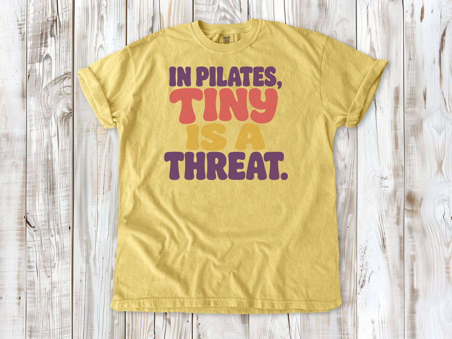 Butter garment-dyed tee with In Pilates Tiny Is a Threat studio humor graphic.