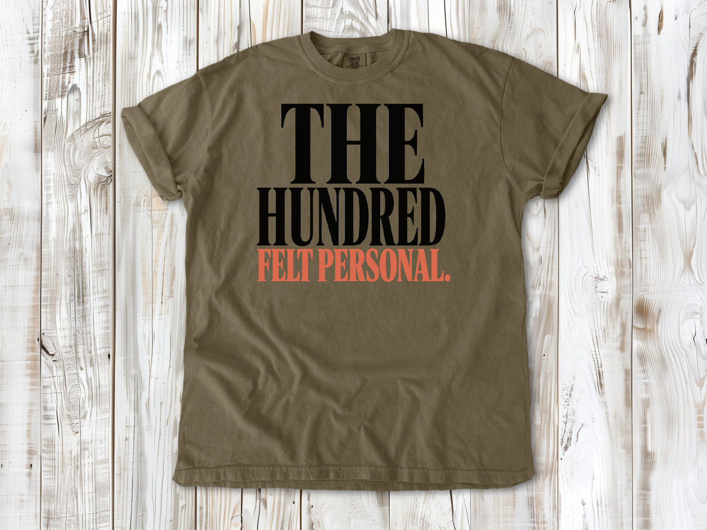 Khaki garment-dyed tee with The Hundred Felt Personal Pilates exercise graphic.