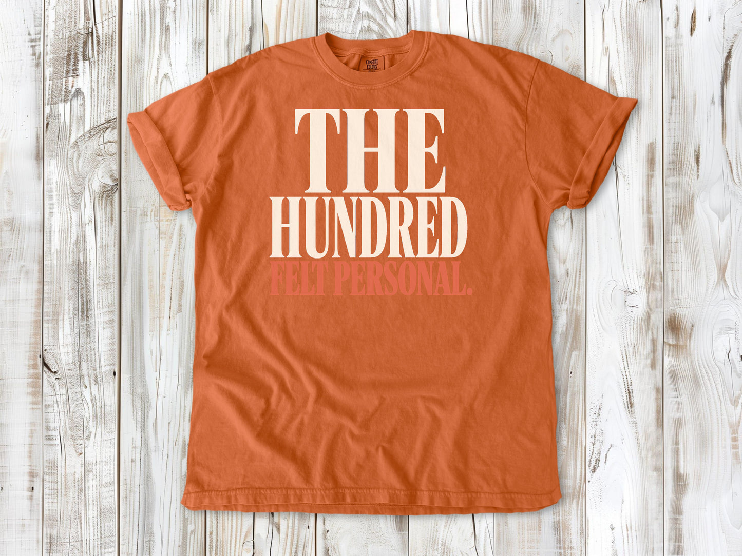 Burnt Orange garment-dyed tee with The Hundred Felt Personal Pilates exercise graphic.