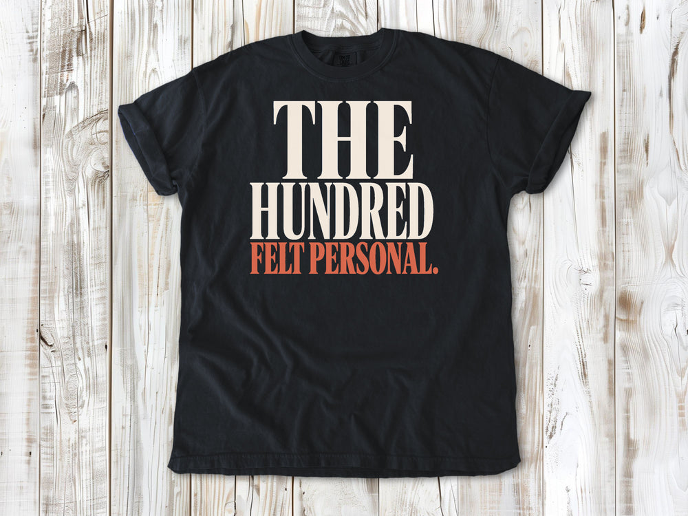 Graphite garment-dyed tee with The Hundred Felt Personal Pilates exercise graphic.